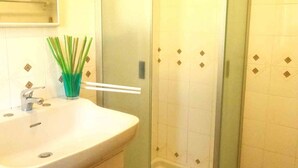 Un baño con lavamanos, espejo y zona de ducha.