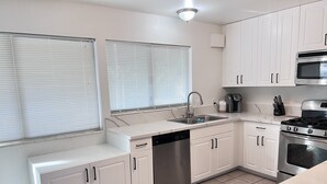 A modern kitchen with white cabinets, a stainless steel dishwasher, a sink, a stove, and a microwave. - Big monthly discount. Professional travelers,relocating or just visiting. (Henderson)