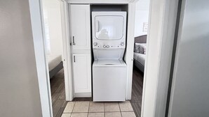 A laundry room with a front-loading washer and dryer, a door leading to a bedroom, and a ceiling light fixture. - Big monthly discount. Professional travelers,relocating or just visiting. (Henderson)