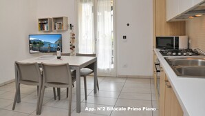 Una cocina moderna con estufa, lavamanos y comedor con sillas y una mesa.