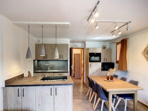 A modern kitchen with a central island, pendant lights, and a dining area with chairs and a table. - Stunning 3 Room 6 Pers, Ski-in/Ski-out, 2 Bed, South (Les Menuires)