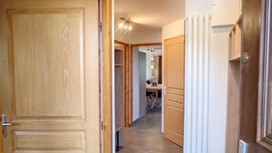 Un pasillo con puertas de madera, un radiador blanco y una cocina a lo lejos.