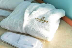 A white towel with a logo and text, and a white footrest on a tiled surface. - Lovely Seaview Apartment in Chania (Apokoronas)