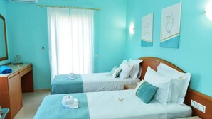 Habitación de hotel con dos camas, un escritorio, un espejo y obras de arte en las paredes.