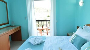 Un dormitorio con cama, escritorio y balcón con mesa y sillas.