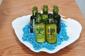 A white plate with four bottles of Olive Tree body lotion and conditioner, surrounded by blue crystals. - Lovely Seaview Apartment in Chania (Apokoronas)