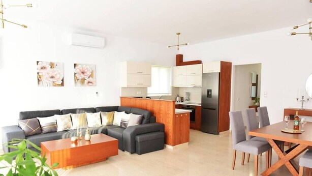 Una sala moderna con sofá, mesa de centro y comedor con sillas y una mesa.