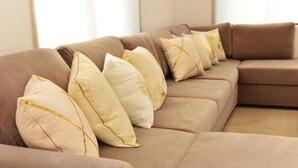 Ein hellbraunes, modulares Sofa mit vielen Kissen in einem Wohnzimmer.