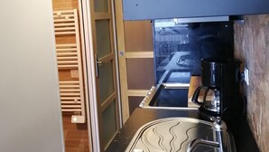 Una cucina compatta con forno a incasso, macchina del caffè e vista sulla strada tramite una porta vetrata.
