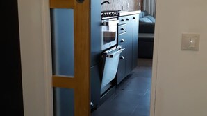 Una cucina con forno a incasso e piano cottura, una porta in legno e un pavimento piastrellato.