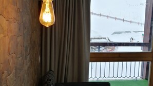 Una stanza con parete in mattoni, lampadario a sospensione, finestra vista su un paesaggio innevato e una recinzione.