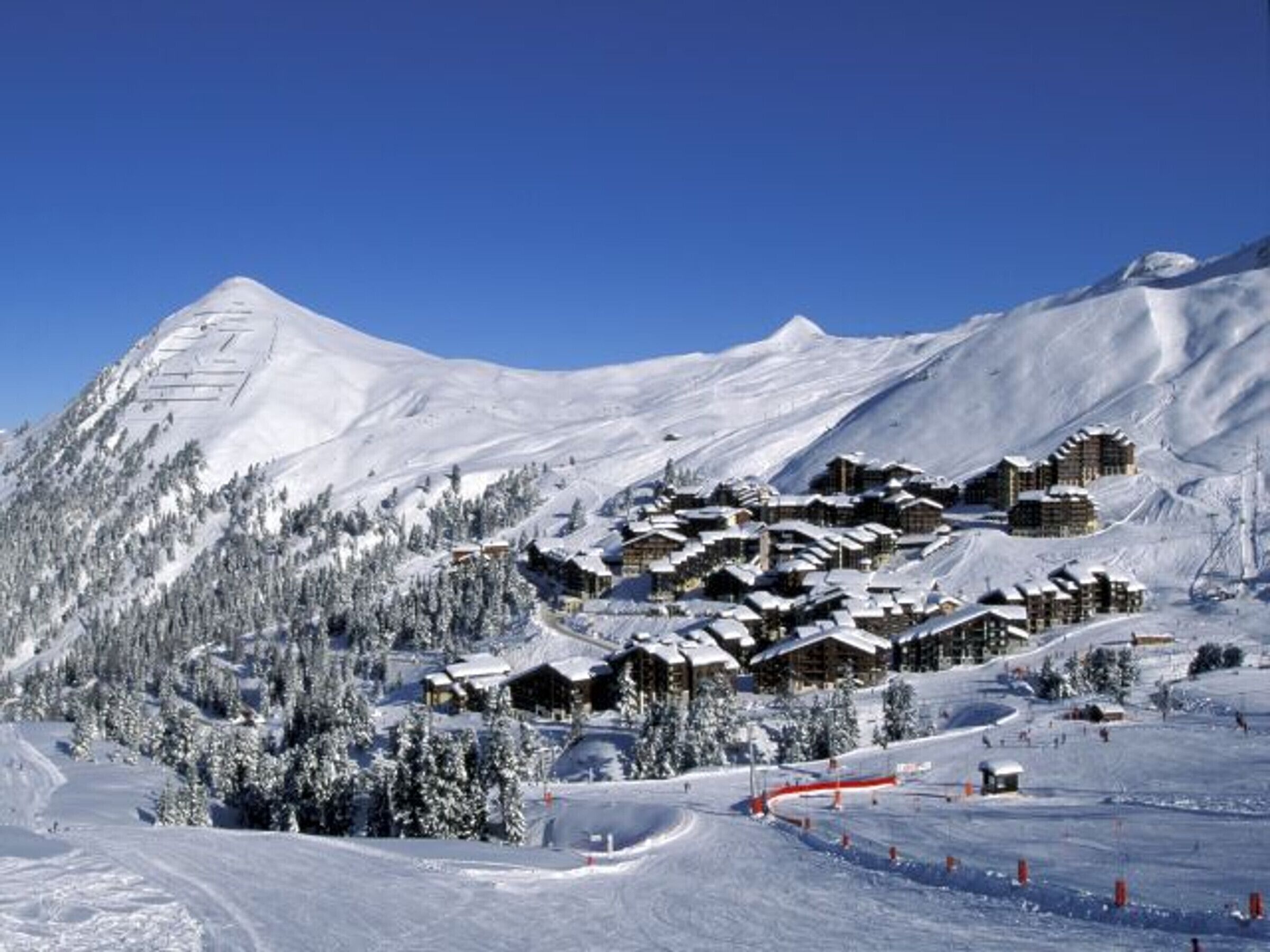 A snow-covered mountain with a cluster of wooden chalets.