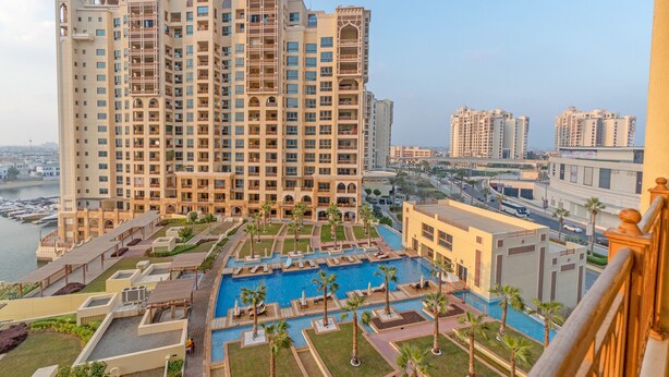 A high-rise hotel with multiple balconies, a swimming pool, and a marina in the background. - Splendid View 2 Bedroom Apartment in the Palm Jumeirah (Dubai)