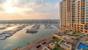 A marina with boats, a large building with balconies, and a pool area. - Splendid View 2 Bedroom Apartment in the Palm Jumeirah (Dubai)