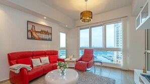 A modern living room with a red sofa, a white coffee table, and a large window overlooking a marina. - Splendid View 2 Bedroom Apartment in the Palm Jumeirah (Dubai)