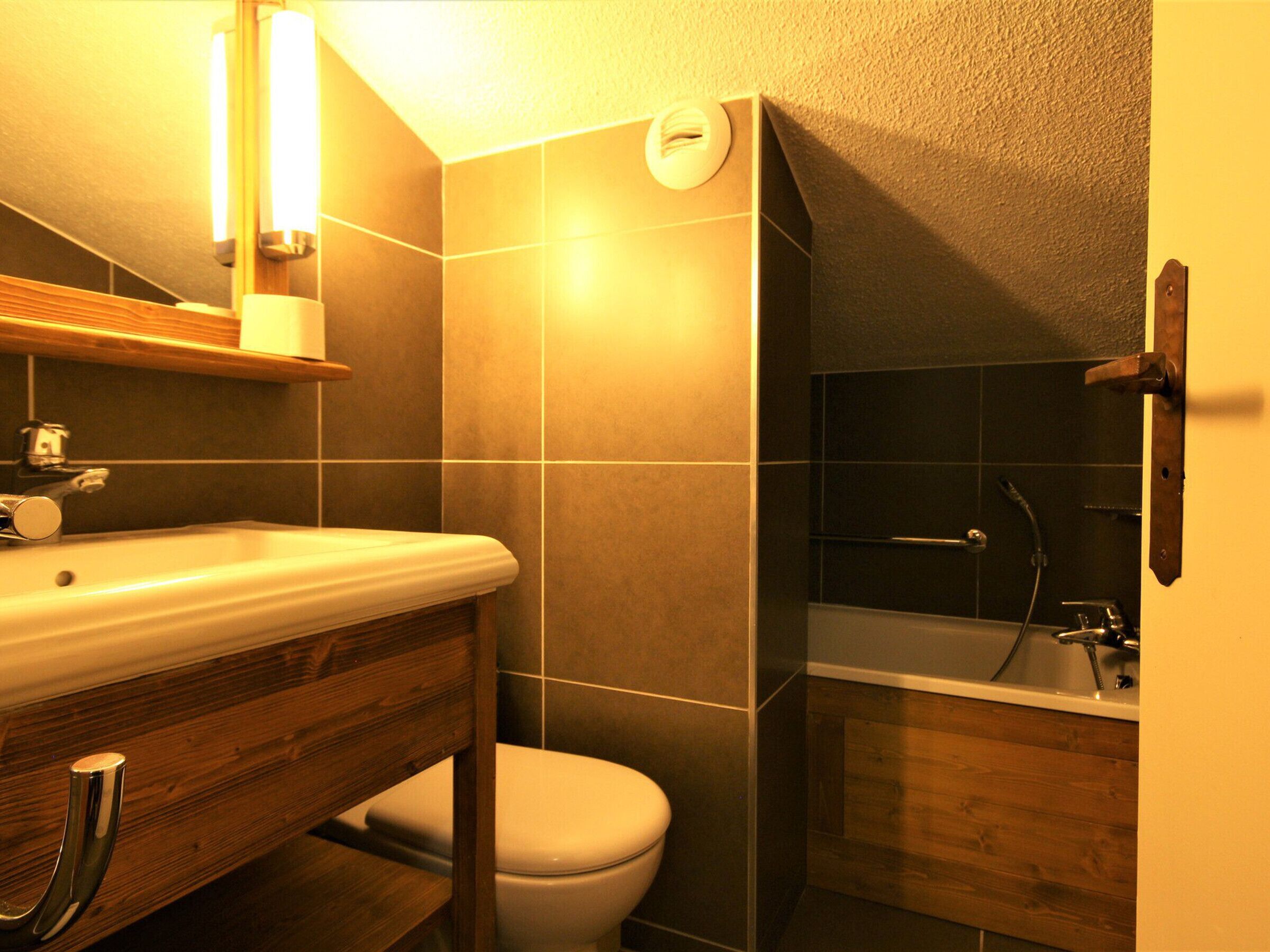 Un bagno con un mobile vanitario in legno, un water e una vasca da bagno.