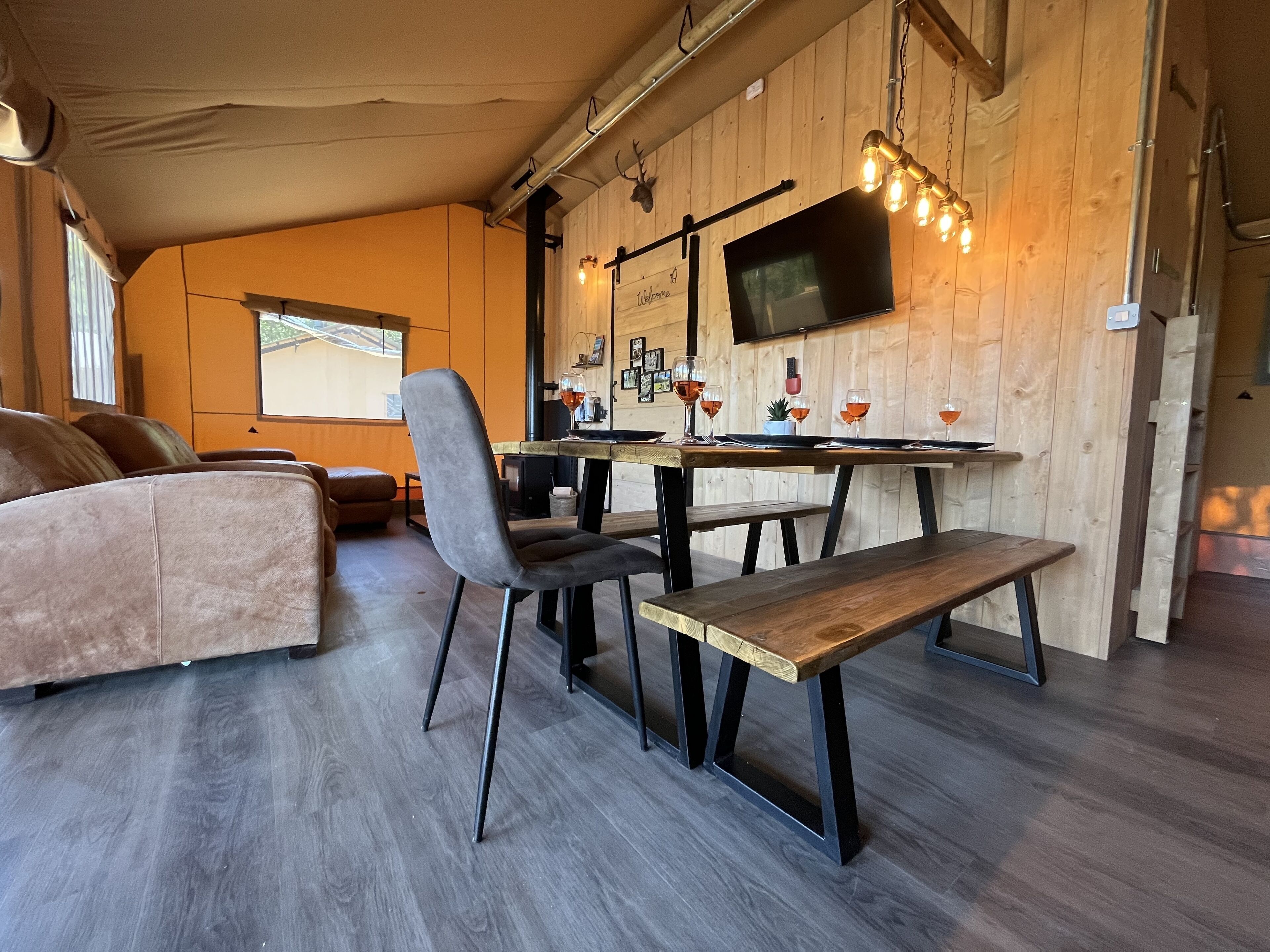 Un salón acogedor con sofá, una mesa de comedor con sillas, un televisor en la pared y un banco de madera.