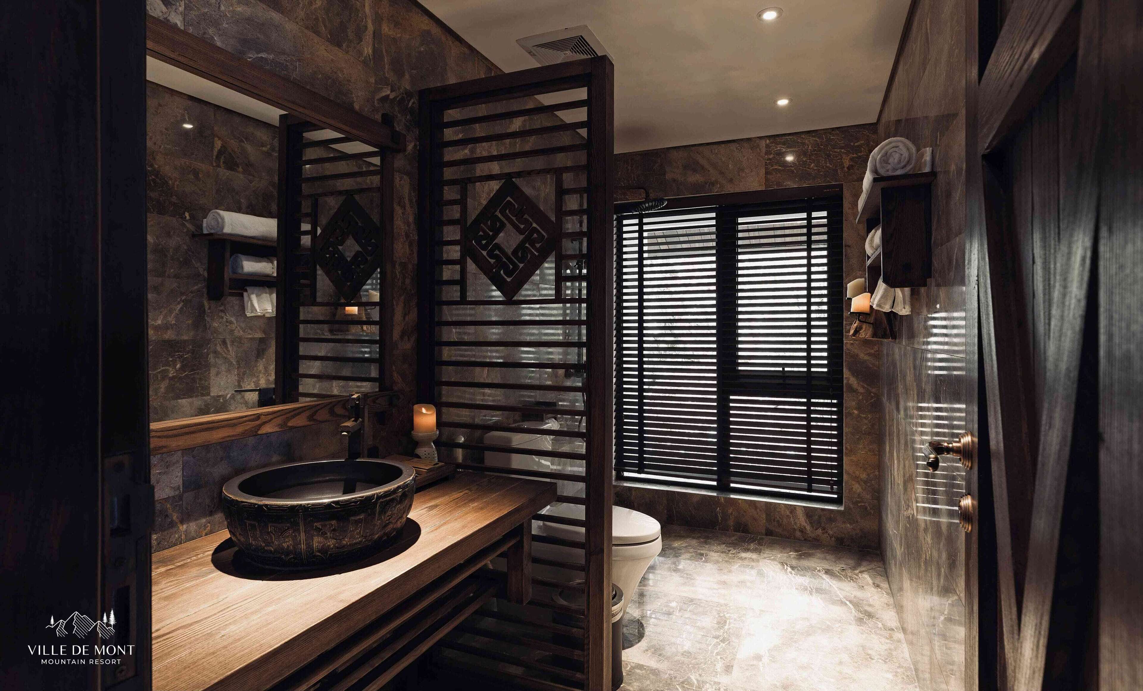 A bathroom with a stone sink, a toilet, and a window with blinds.