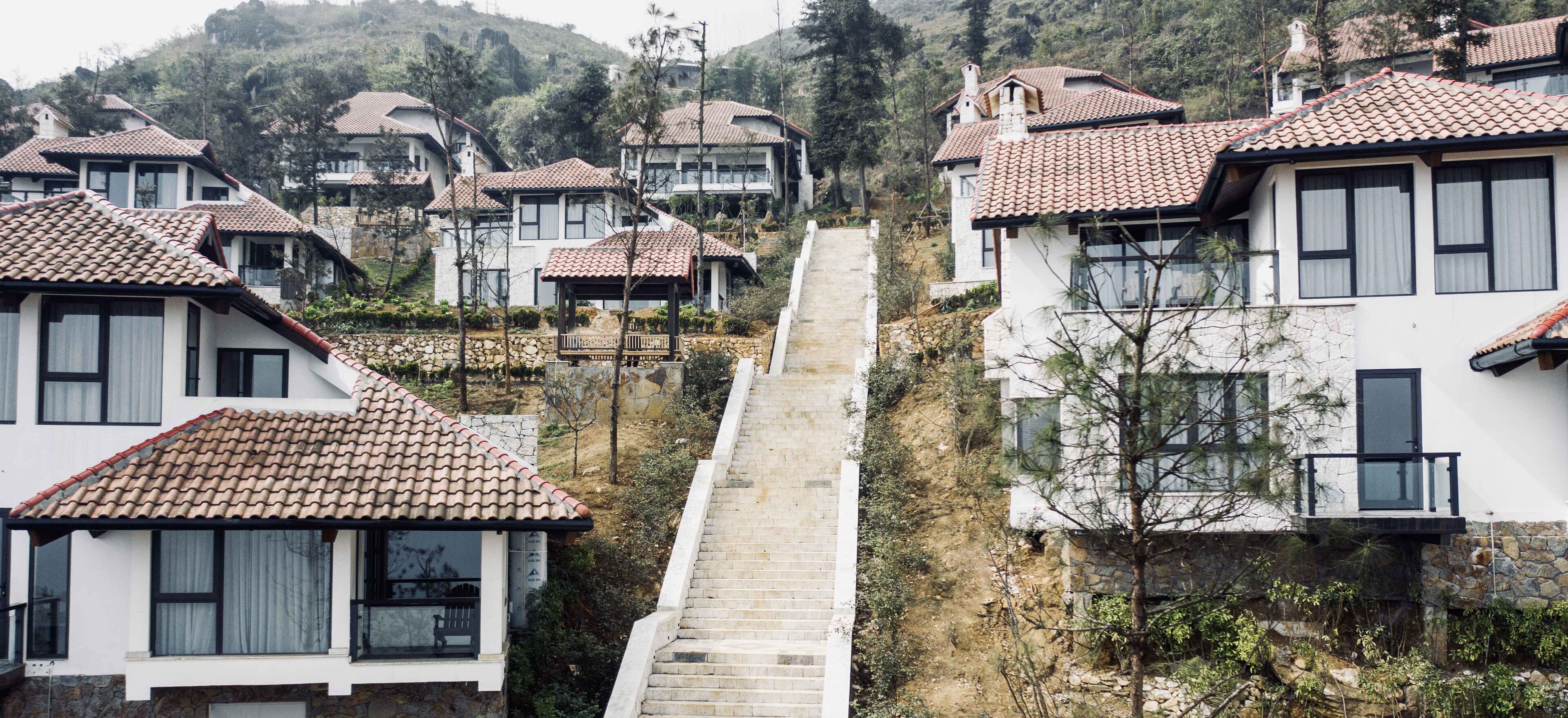 A residential area with houses featuring tiled roofs and a central staircase leading uphill.