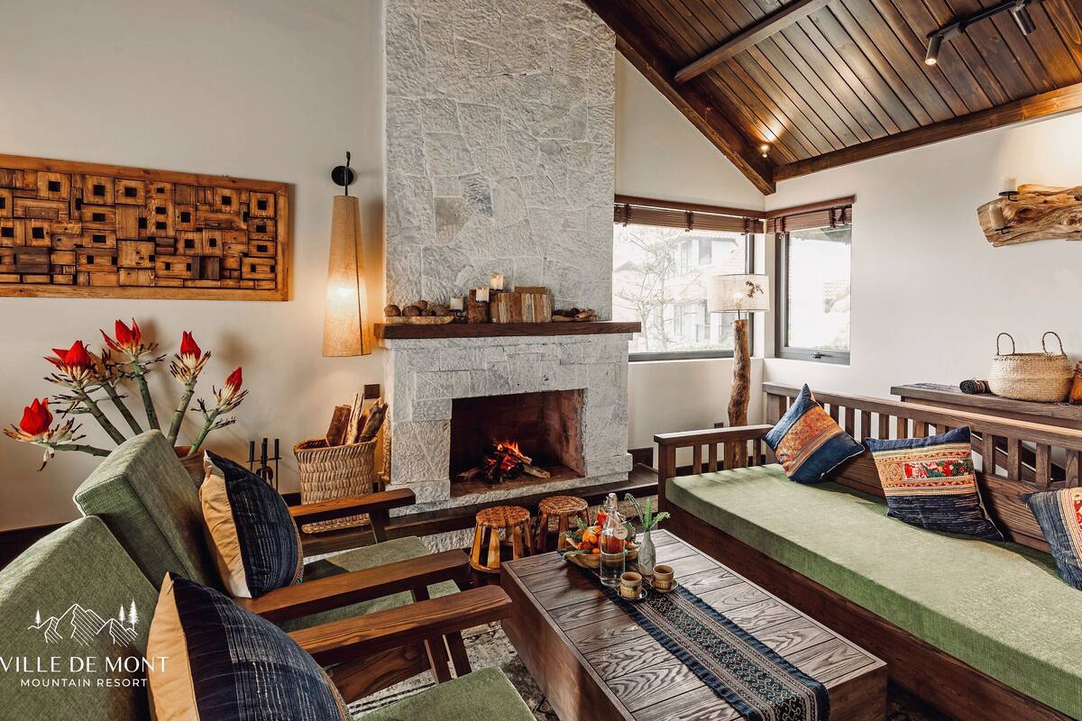 Una sala de estar acogedora con chimenea de piedra, muebles de madera y vistas al exterior.