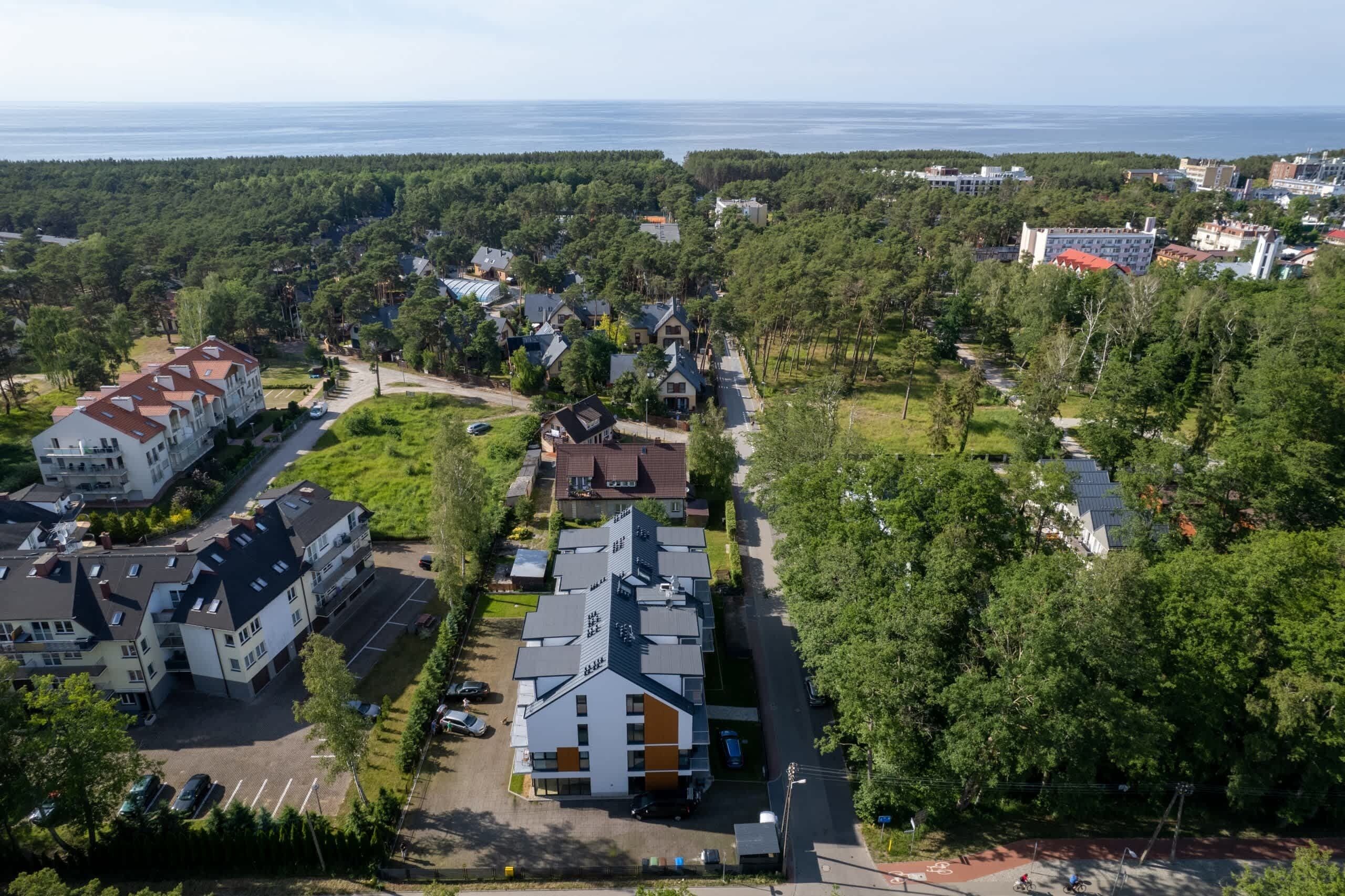 Vista aérea de una zona residencial con varios edificios, carreteras y una masa de agua al fondo.