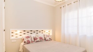 A bedroom with a bed, a headboard with a geometric pattern, and a window with curtains. - Saule Apartment, Swimming Pool, Terrace !new! (Lagos)