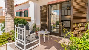 A patio with a white metal chair, a small table, and potted plants. - Saule Apartment, Swimming Pool, Terrace !new! (Lagos)