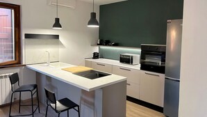 A modern kitchen with a central island, pendant lighting, a built-in oven, and a refrigerator. - House I Limori with garden and parking (Gello)
