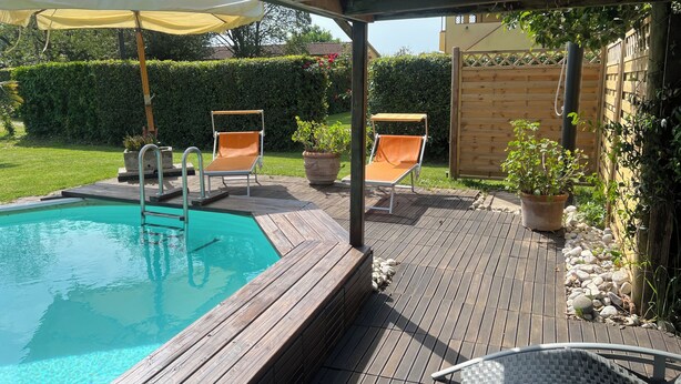 A wooden deck with a swimming pool, two lounge chairs, and a pergola with a canopy. - House I Limori with garden and parking (Gello)