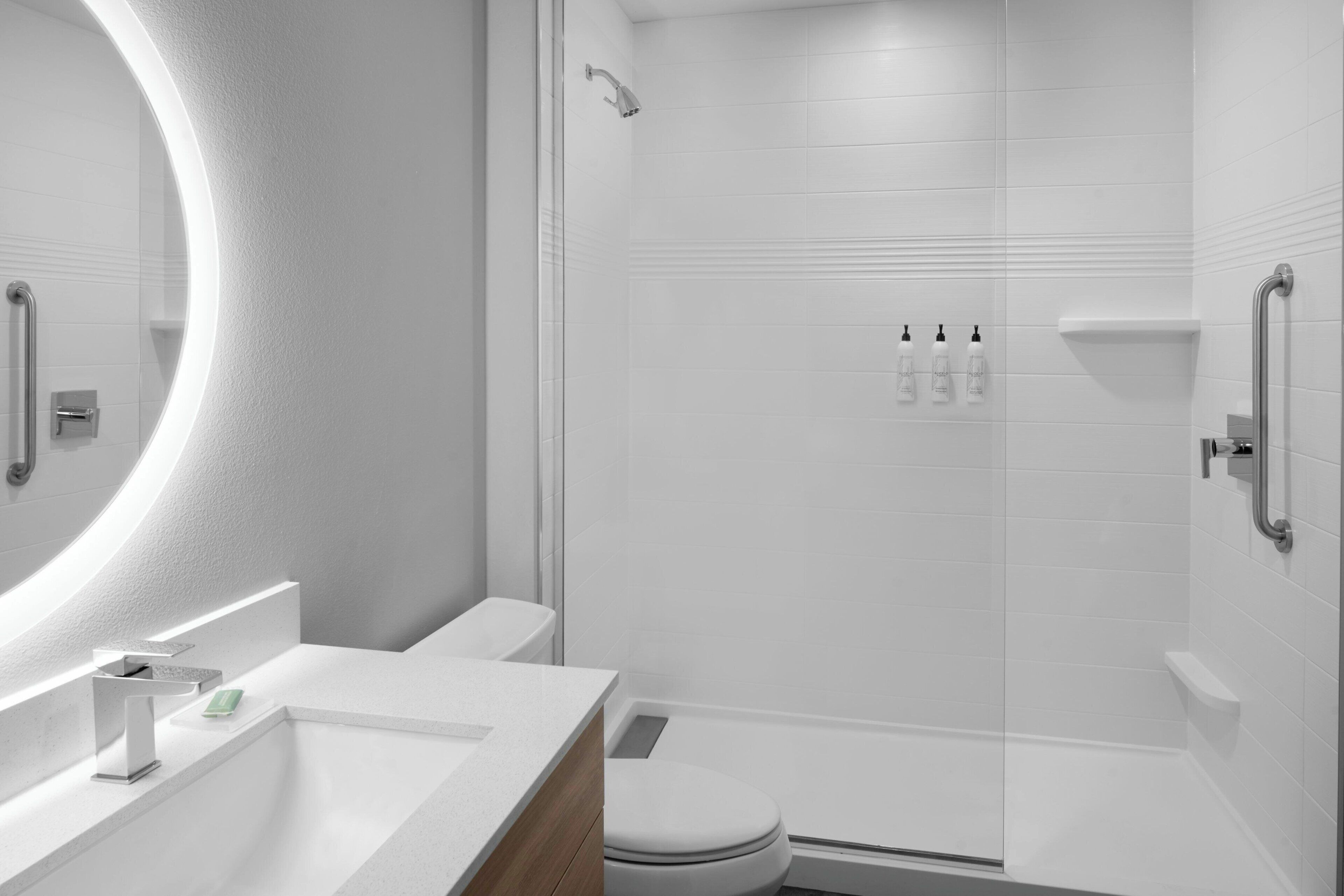 A modern bathroom with a glass-enclosed shower, a white sink with a mirror, and a toilet.