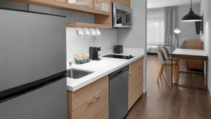 Una cocina moderna con lavavajillas, cafetera y microondas. Cuenta con un comedor con mesa y sillas.