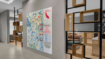 A modern interior with a large abstract artwork on the wall, a reception desk, and a seating area with a sofa and a coffee table.