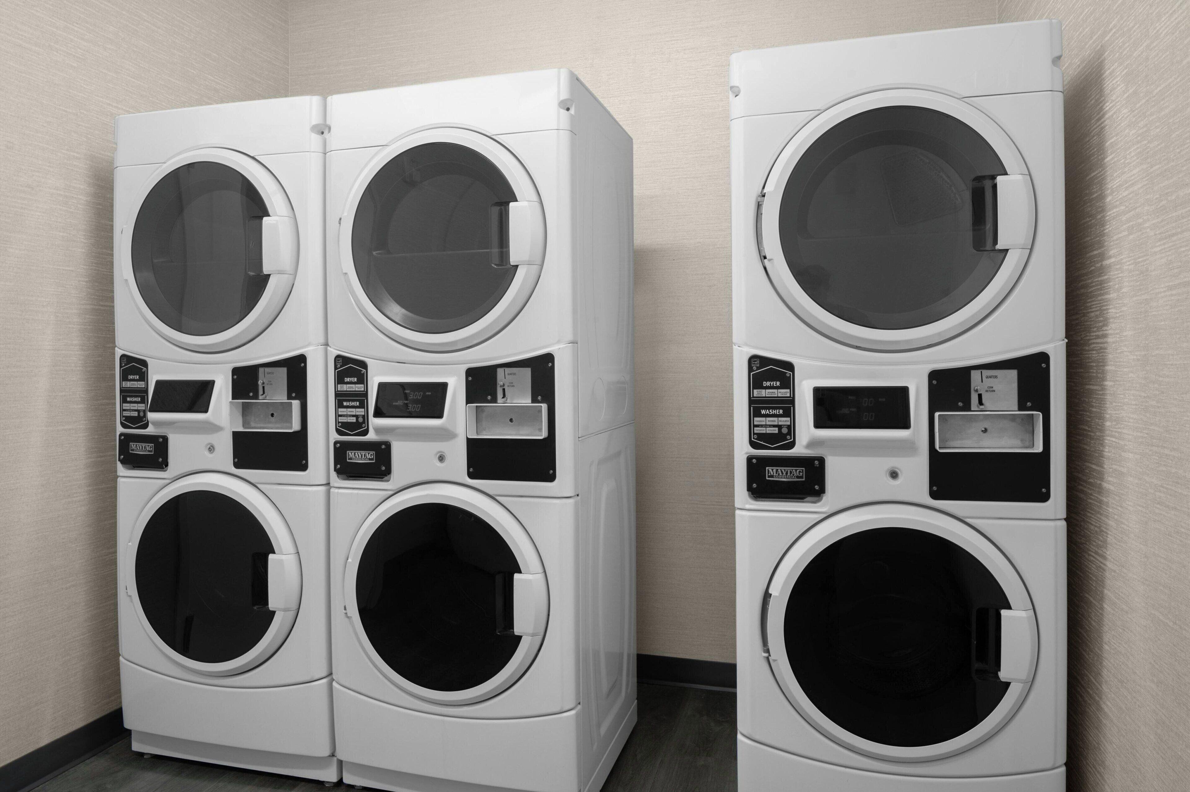 Two stacked front-loading washing machines in a laundry room.