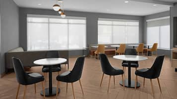 A modern dining area with round tables and black chairs, large windows, and a grey wall.