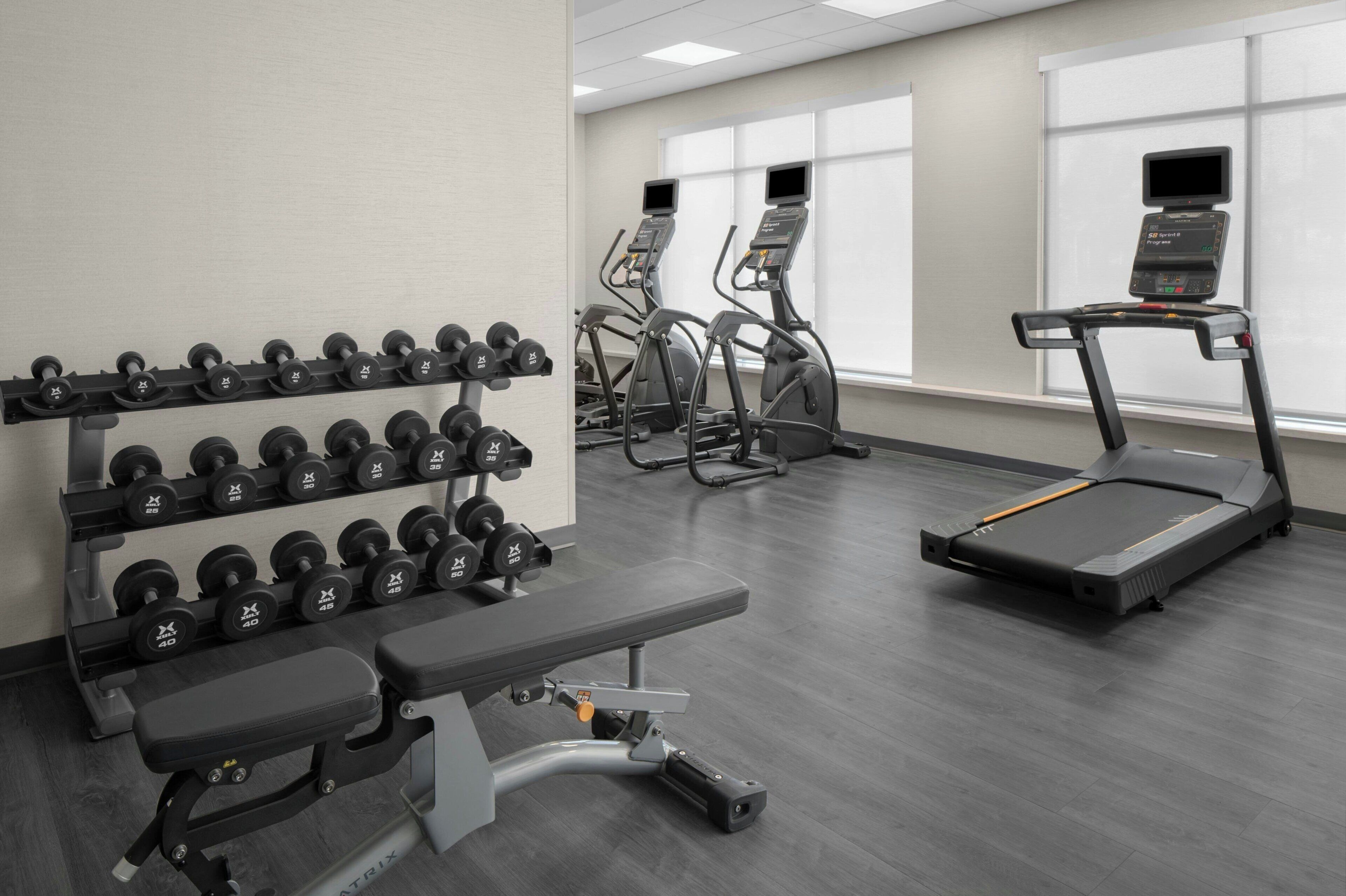 A gym with treadmills, elliptical machines, and a bench press.