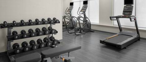 A gym with treadmills, elliptical machines, and a bench press.
