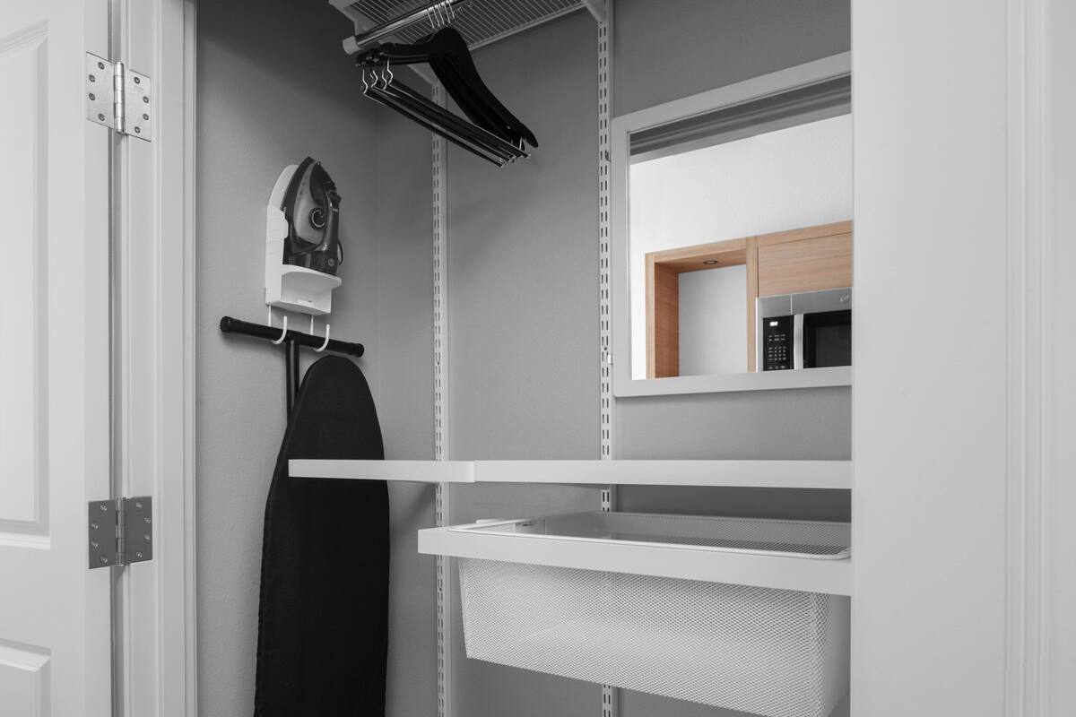 Een moderne keuken met witte kastjes, een magnetron en een hangrek.
