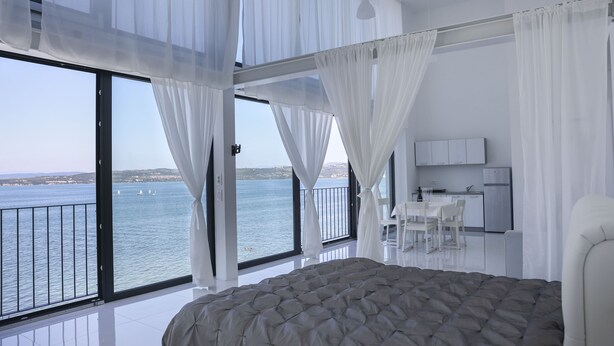 A bedroom with a large bed, a balcony with a view of the sea, and a small kitchenette. - Villa Molet (Koper)