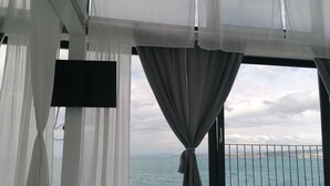 A room with a large window overlooking the sea, a bed, and a flat-screen TV mounted on the wall. - Villa Molet (Koper)