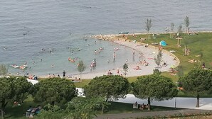 A coastal beach scene with people swimming and sunbathing. - Villa Molet (Koper)