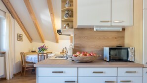 A kitchen with white cabinets, a wooden countertop, a microwave, and a bowl of apples.