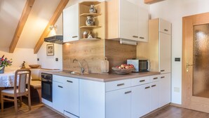 A compact kitchen with white cabinetry, a wooden countertop, a built-in oven, and a microwave.