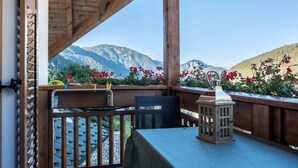 Un balcon en bois avec une table et une chaise, une lanterne et une vue sur les montagnes.