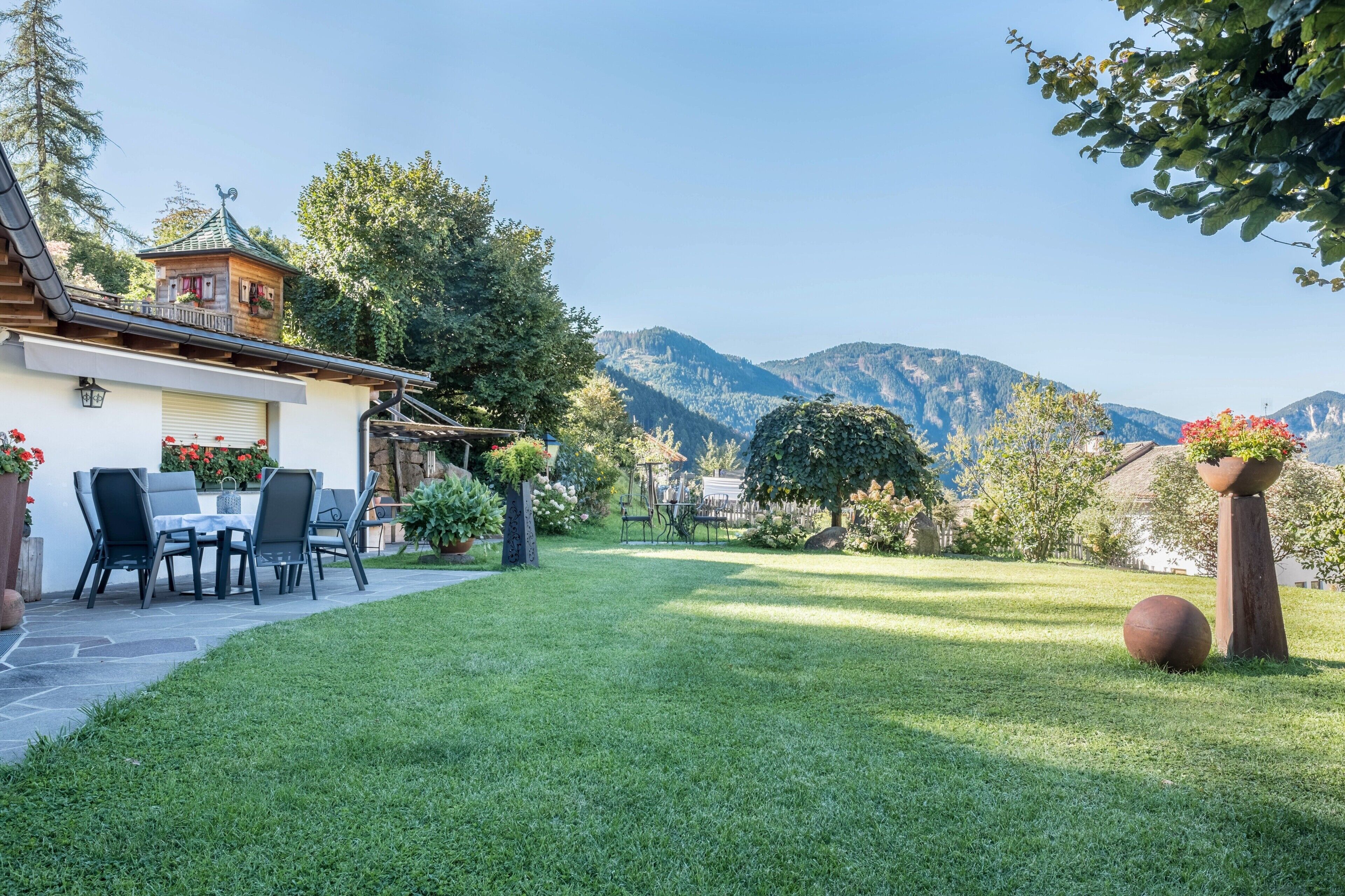 Ein Haus mit Terrasse, Essbereich und Bergblick.