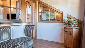 Une pièce avec un escalier en bois, un banc, une armoire en bois et une fenêtre donnant sur un paysage verdoyant.