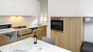 A modern kitchen with white cabinets, a gas stove, a microwave, and a built-in oven.