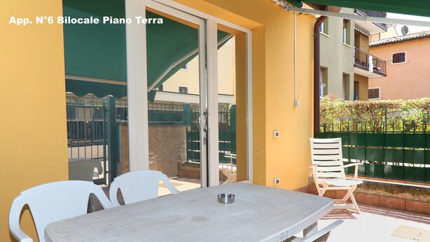 A patio area with a table and chairs, a sliding glass door, and a view of the surrounding buildings.