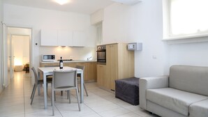 A compact living space with a dining area, kitchenette, and a sofa.