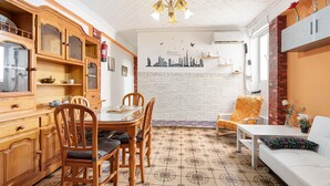 A dining area with a wooden cabinet, a dining table with chairs, a white sofa, and a patterned floor.