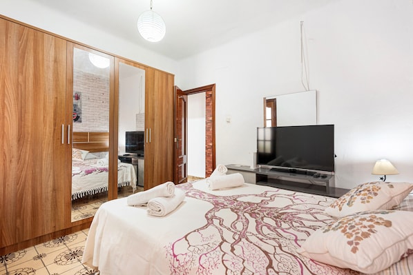 Une chambre à coucher avec un lit, une télévision, une armoire et un miroir.